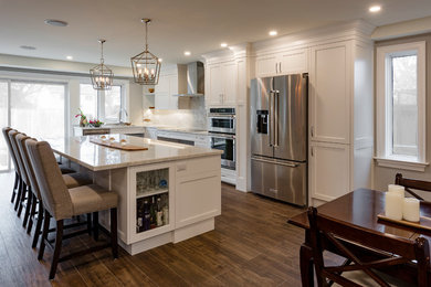Eat-in kitchen - mid-sized contemporary l-shaped medium tone wood floor and brown floor eat-in kitchen idea in Toronto with an integrated sink, shaker cabinets, white cabinets, quartzite countertops, white backsplash, marble backsplash, stainless steel appliances, an island and white countertops