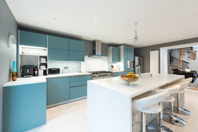 Inspiration for a large contemporary l-shaped open plan kitchen in Other with a submerged sink, flat-panel cabinets, blue cabinets, composite countertops, white splashback, glass sheet splashback, stainless steel appliances, laminate floors and an island.