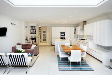 This is an example of a contemporary galley open plan kitchen in London with flat-panel cabinets, white cabinets and an island.