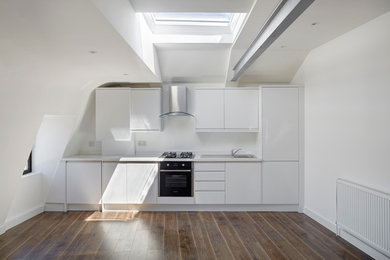Inspiration for a medium sized urban single-wall open plan kitchen in London with a single-bowl sink, flat-panel cabinets, white cabinets, laminate countertops, dark hardwood flooring and no island.