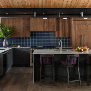 Inspiration for a midcentury l-shaped kitchen in Seattle with an undermount sink, flat-panel cabinets, dark wood cabinets, blue splashback, subway tile splashback, panelled appliances, dark hardwood floors, with island, brown floor and white benchtop.