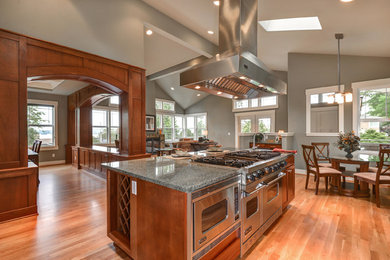 Arts and crafts light wood floor eat-in kitchen photo in Seattle with recessed-panel cabinets, medium tone wood cabinets, granite countertops, stainless steel appliances and an island