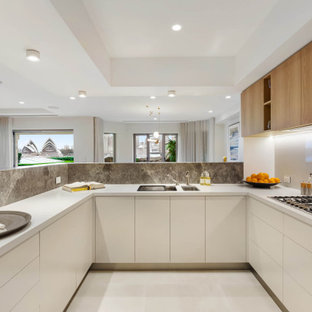 Inspiration for a mid-sized contemporary u-shaped open plan kitchen in Sydney with an undermount sink, flat-panel cabinets, limestone benchtops, white splashback, engineered quartz splashback, black appliances, ceramic floors, white floor, recessed, white cabinets, a peninsula and white benchtop.
