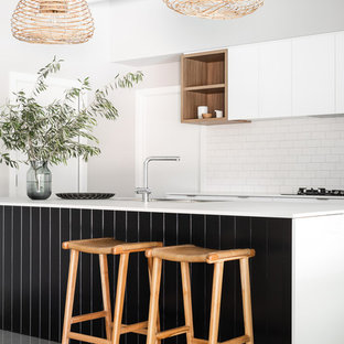 Photo of a contemporary kitchen in Perth with flat-panel cabinets, white cabinets, white splashback, subway tile splashback, with island, grey floor and white benchtop.