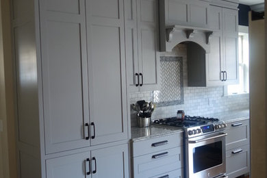 Design ideas for a medium sized traditional l-shaped enclosed kitchen in Providence with flat-panel cabinets, grey cabinets, marble worktops, grey splashback, mosaic tiled splashback, stainless steel appliances and medium hardwood flooring.