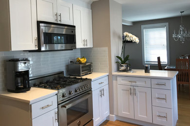 Small transitional l-shaped light wood floor and beige floor eat-in kitchen photo in Bridgeport with an undermount sink, shaker cabinets, white cabinets, gray backsplash, glass tile backsplash, stainless steel appliances, no island and quartzite countertops