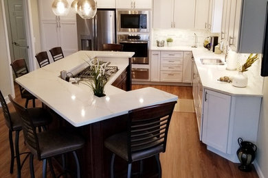 Example of a large transitional l-shaped medium tone wood floor and brown floor open concept kitchen design in Chicago with shaker cabinets, white cabinets, quartzite countertops, white backsplash, an island, a double-bowl sink and stainless steel appliances