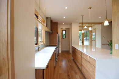 Example of a mid-sized eclectic galley light wood floor open concept kitchen design in Other with an undermount sink, medium tone wood cabinets, quartz countertops, glass sheet backsplash, stainless steel appliances, an island and white countertops
