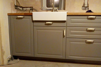 Photo of a medium sized classic open plan kitchen in Other with a belfast sink, raised-panel cabinets, grey cabinets, wood worktops and brown worktops.