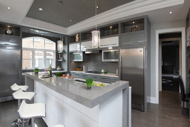 Large minimalist l-shaped porcelain tile enclosed kitchen photo in Toronto with a double-bowl sink, flat-panel cabinets, gray cabinets, granite countertops, gray backsplash, matchstick tile backsplash, stainless steel appliances and an island