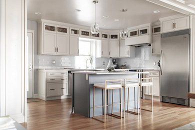 Eat-in kitchen - mid-sized transitional l-shaped light wood floor eat-in kitchen idea in New York with a farmhouse sink, white cabinets, marble countertops, white backsplash, subway tile backsplash, stainless steel appliances, an island and gray countertops