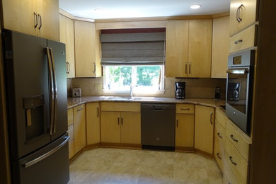 Example of a mid-sized classic u-shaped laminate floor and beige floor eat-in kitchen design in Other with an undermount sink, flat-panel cabinets, light wood cabinets, granite countertops, beige backsplash, no island, multicolored countertops, ceramic backsplash and stainless steel appliances
