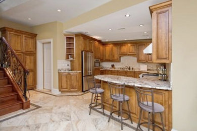 Example of a classic kitchen design in Chicago with granite countertops, white cabinets, beige backsplash, stainless steel appliances and a peninsula