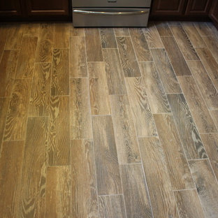 Mid-sized traditional eat-in kitchen designs - Example of a mid-sized classic u-shaped porcelain tile eat-in kitchen design in Cleveland with a double-bowl sink, raised-panel cabinets, medium tone wood cabinets, laminate countertops, gray backsplash, glass tile backsplash, stainless steel appliances and a peninsula