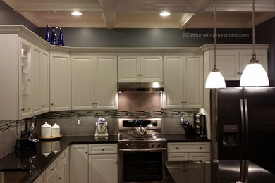 Eat-in kitchen - large traditional l-shaped dark wood floor eat-in kitchen idea in Philadelphia with a single-bowl sink, raised-panel cabinets, white cabinets, granite countertops, gray backsplash, ceramic backsplash, stainless steel appliances and an island