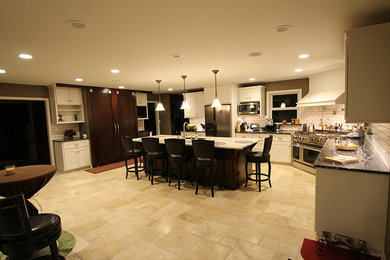 Example of a travertine floor open concept kitchen design in Milwaukee with a double-bowl sink, recessed-panel cabinets, white cabinets, marble countertops, white backsplash, subway tile backsplash, stainless steel appliances and an island