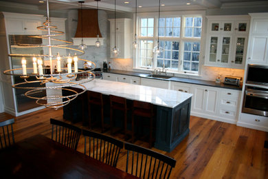 Eat-in kitchen - large traditional l-shaped medium tone wood floor, brown floor and coffered ceiling eat-in kitchen idea in Boston with an undermount sink, shaker cabinets, white cabinets, marble countertops, white backsplash, marble backsplash, stainless steel appliances, an island and white countertops
