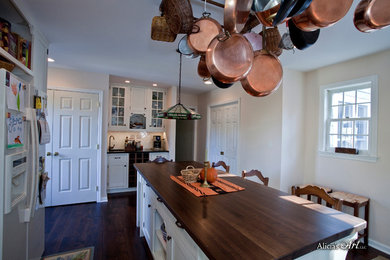 Example of a mid-sized classic l-shaped dark wood floor eat-in kitchen design in Philadelphia with an undermount sink, shaker cabinets, white cabinets, wood countertops, beige backsplash, white appliances and an island