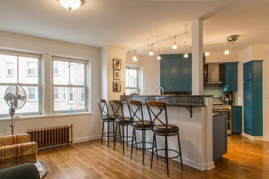 Example of a mid-sized minimalist light wood floor eat-in kitchen design in Chicago with a farmhouse sink, shaker cabinets, blue cabinets, quartz countertops, gray backsplash, subway tile backsplash, stainless steel appliances and an island