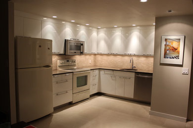 Cette photo montre une cuisine américaine moderne en L avec un évier encastré, un placard à porte plane, des portes de placard blanches, un plan de travail en quartz modifié, une crédence marron et un électroménager blanc.