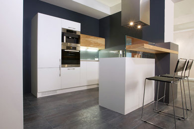 Small modern u-shaped kitchen/diner in Other with a single-bowl sink, flat-panel cabinets, white cabinets, laminate countertops, grey splashback, glass sheet splashback, stainless steel appliances, laminate floors and a breakfast bar.