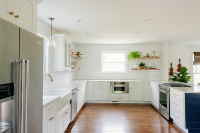 Inspiration for a large timeless u-shaped medium tone wood floor and brown floor eat-in kitchen remodel in Nashville with a farmhouse sink, shaker cabinets, white cabinets, quartz countertops, white backsplash, subway tile backsplash, stainless steel appliances, an island and white countertops