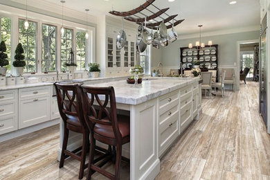 Kitchen - cottage porcelain tile kitchen idea in Chicago with raised-panel cabinets, white cabinets, marble countertops, stainless steel appliances and an island