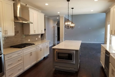Mid-sized country eat-in kitchen photo in Atlanta with shaker cabinets, white cabinets, quartzite countertops, gray backsplash, an island, white countertops, a farmhouse sink, subway tile backsplash and stainless steel appliances