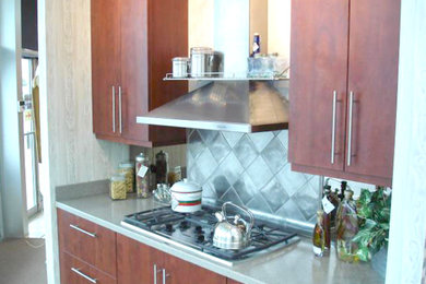 Ejemplo de cocina tradicional renovada con armarios con paneles lisos, puertas de armario de madera en tonos medios y salpicadero metalizado