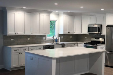 Mid-sized transitional l-shaped dark wood floor and brown floor enclosed kitchen photo in Chicago with an undermount sink, shaker cabinets, white cabinets, marble countertops, gray backsplash, subway tile backsplash, stainless steel appliances, an island and white countertops