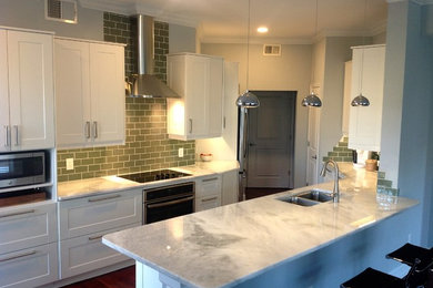 Eat-in kitchen - mid-sized transitional l-shaped medium tone wood floor eat-in kitchen idea in Orlando with a double-bowl sink, shaker cabinets, white cabinets, marble countertops, green backsplash, subway tile backsplash, stainless steel appliances and a peninsula
