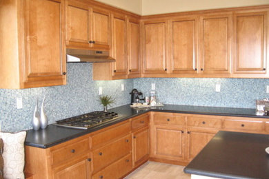サクラメントにあるおしゃれなアイランドキッチン (中間色木目調キャビネット、セラミックタイルのキッチンパネル、淡色無垢フローリング) の写真