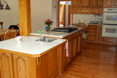 Open concept kitchen - large l-shaped medium tone wood floor open concept kitchen idea in Cleveland with a drop-in sink, medium tone wood cabinets, beige backsplash, white appliances and an island