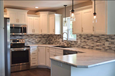 Example of a mid-sized transitional u-shaped brown floor and dark wood floor enclosed kitchen design with an undermount sink, stainless steel appliances, shaker cabinets, white cabinets, quartzite countertops, multicolored backsplash, ceramic backsplash and no island