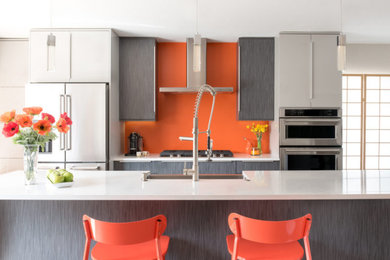 デンバーにあるコンテンポラリースタイルのおしゃれなキッチン (エプロンフロントシンク、フラットパネル扉のキャビネット、グレーのキャビネット、オレンジのキッチンパネル、シルバーの調理設備、白いキッチンカウンター) の写真