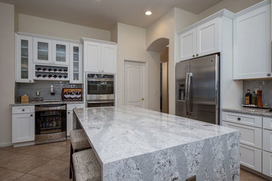 Example of a mid-sized transitional u-shaped ceramic tile and brown floor eat-in kitchen design in Phoenix with shaker cabinets, white cabinets, quartz countertops, gray backsplash, glass tile backsplash, an island, an undermount sink and stainless steel appliances