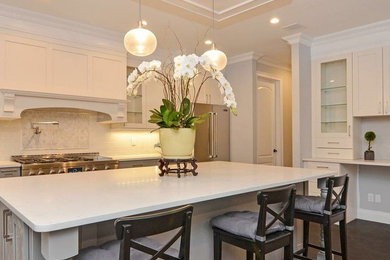 Large transitional single-wall dark wood floor and brown floor eat-in kitchen photo in New York with a farmhouse sink, flat-panel cabinets, white cabinets, quartzite countertops, white backsplash, glass tile backsplash, stainless steel appliances, an island and white countertops