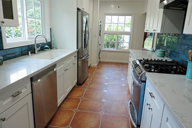 Small porcelain tile and orange floor enclosed kitchen photo in Los Angeles with an undermount sink, shaker cabinets, white cabinets, quartz countertops, blue backsplash, porcelain backsplash, stainless steel appliances and white countertops