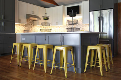 Open concept kitchen - mid-sized modern l-shaped medium tone wood floor and brown floor open concept kitchen idea in Other with shaker cabinets, white cabinets, quartzite countertops, multicolored backsplash, glass sheet backsplash, stainless steel appliances, an island, an undermount sink and white countertops