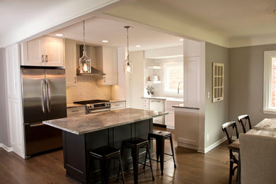 Inspiration for a mid-sized modern l-shaped medium tone wood floor eat-in kitchen remodel in Detroit with a farmhouse sink, recessed-panel cabinets, white cabinets, granite countertops, white backsplash, subway tile backsplash, stainless steel appliances and an island