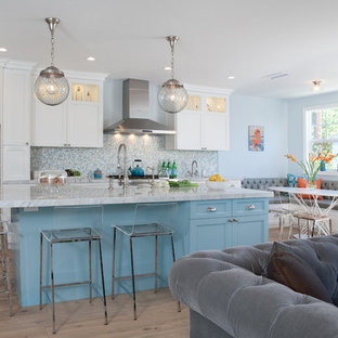 Large coastal eat-in kitchen ideas - Example of a large beach style l-shaped medium tone wood floor eat-in kitchen design in Los Angeles with a farmhouse sink, shaker cabinets, white cabinets, blue backsplash, mosaic tile backsplash, stainless steel appliances, an island and marble countertops