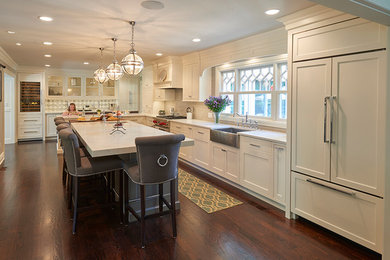 Inspiration for a large timeless l-shaped dark wood floor enclosed kitchen remodel in New York with a farmhouse sink, shaker cabinets, white cabinets, marble countertops, white backsplash, subway tile backsplash, paneled appliances and an island