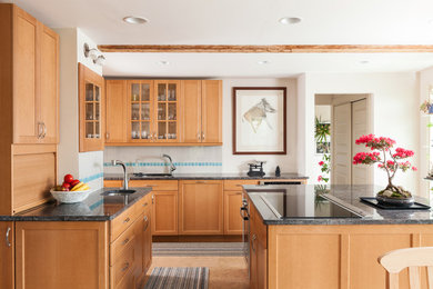 Photo of a medium sized traditional l-shaped kitchen/diner in Boston with a submerged sink, recessed-panel cabinets, light wood cabinets, granite worktops, beige splashback, ceramic splashback, stainless steel appliances, cork flooring and an island.