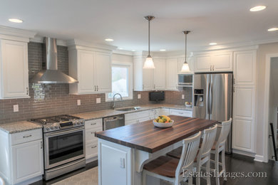 Mid-sized minimalist l-shaped plywood floor and black floor eat-in kitchen photo in New York with an undermount sink, raised-panel cabinets, white cabinets, quartz countertops, gray backsplash, glass tile backsplash, stainless steel appliances, an island and brown countertops