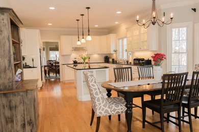 Mid-sized elegant l-shaped light wood floor and brown floor eat-in kitchen photo in Boston with an undermount sink, raised-panel cabinets, white cabinets, quartzite countertops, white backsplash, subway tile backsplash, stainless steel appliances and an island