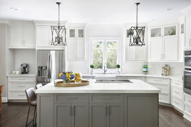 Large transitional l-shaped dark wood floor and brown floor kitchen photo in Atlanta with a farmhouse sink, shaker cabinets, white cabinets, quartz countertops, white backsplash, stainless steel appliances, an island, white countertops and subway tile backsplash