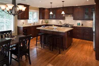 Eat-in kitchen - mid-sized modern u-shaped medium tone wood floor eat-in kitchen idea in Vancouver with an undermount sink, recessed-panel cabinets, dark wood cabinets, granite countertops, beige backsplash and stainless steel appliances