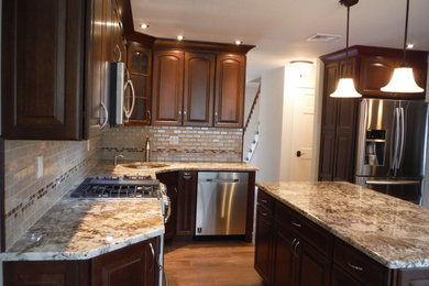 Example of a large transitional l-shaped medium tone wood floor eat-in kitchen design in New York with an undermount sink, raised-panel cabinets, dark wood cabinets, granite countertops, beige backsplash, ceramic backsplash, stainless steel appliances and a peninsula