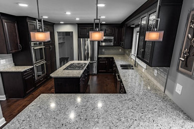 Inspiration for a large transitional u-shaped dark wood floor and brown floor eat-in kitchen remodel in Cleveland with an undermount sink, raised-panel cabinets, dark wood cabinets, quartz countertops, gray backsplash, subway tile backsplash, stainless steel appliances and an island