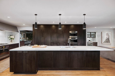 Example of a large trendy light wood floor and brown floor eat-in kitchen design in Other with a double-bowl sink, flat-panel cabinets, dark wood cabinets, quartz countertops, white backsplash, stone slab backsplash, stainless steel appliances, an island and white countertops